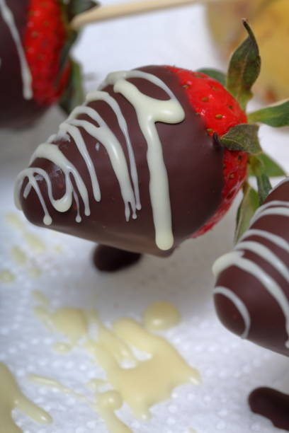 istock Strawberries glazed in black and white chocolate dries on a plate. On the work surface visible drops of chocolate. Cooking strawberries glazed in chocolate. 1140817788