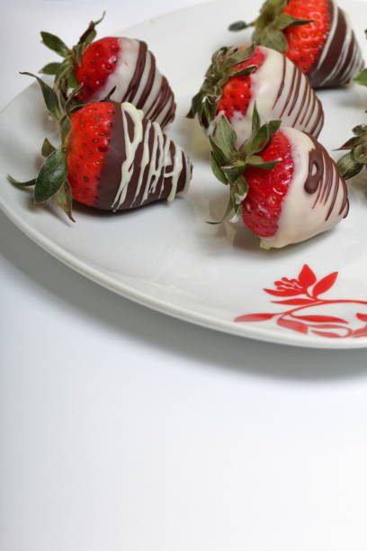 istock Strawberries glazed in black and white chocolate. Lie on a white plate with a pattern. 1140817803