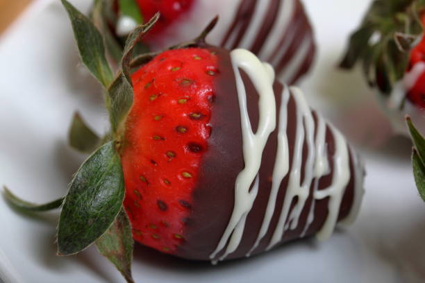 istock Strawberries glazed in black and white chocolate. Lie on a white plate with a pattern. 1140817805