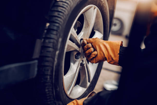 istock Close up of auto mechanic changing tire in workshop. 1140818670