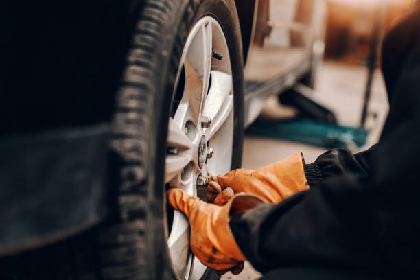 istock Close up of auto mechanic changing tire in workshop. 1140818702