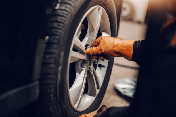 istock Close up of auto mechanic changing tire in workshop. 1140818712