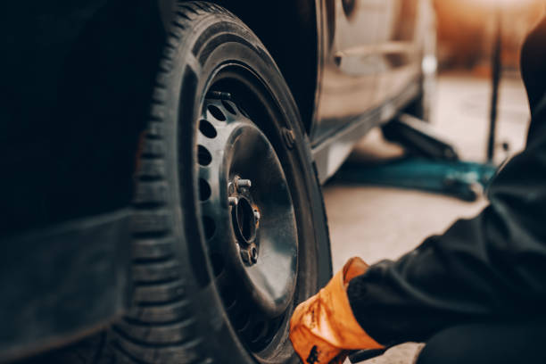 istock Close up of auto mechanic changing tire in workshop. 1140818718