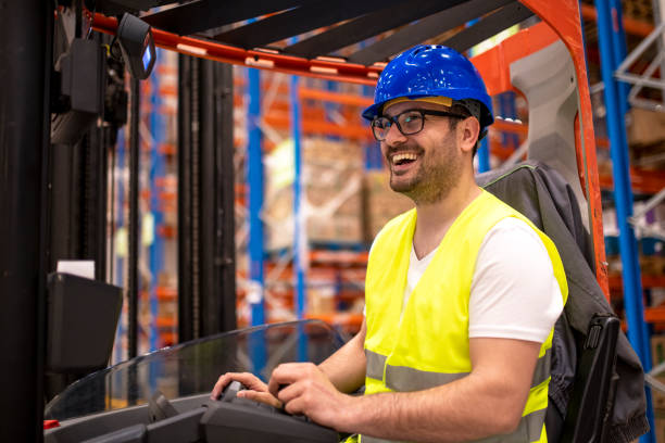 istock Smiling industrial worker driving forklift in big warehouse distribution center. 1140818958