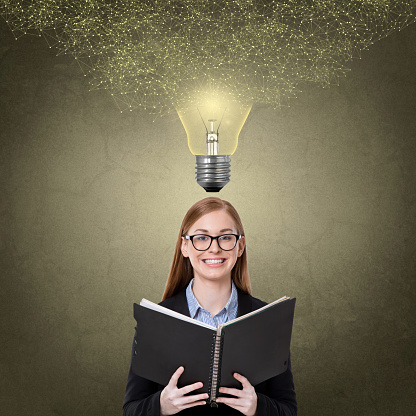 Woman holding diary under light bulb
