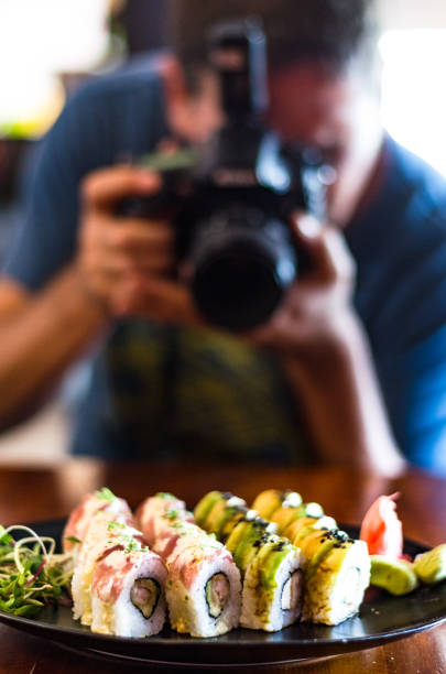 People, leisure, food, food and technology - close up of man with camera taking a picture of sushi in the restaurant stock photo