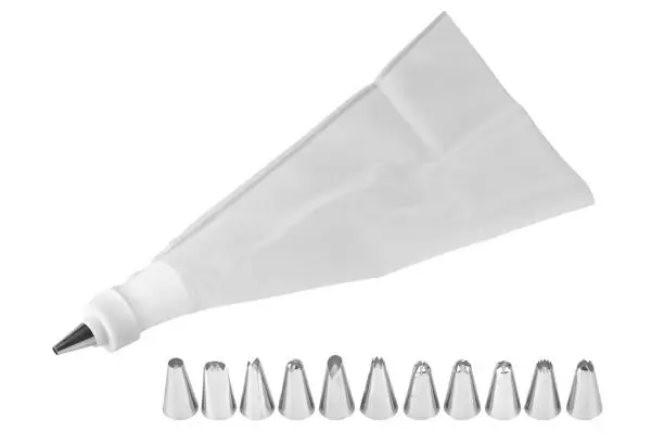 Piping bag for whipped cream frosting with several tips. Cupcake decorating tools, icing bag and nibs, isolated on white background, clipping paths included