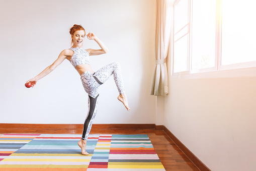 Full length body of beautiful woman dancing in her room at home with apple in her hand. Happiness woman concept