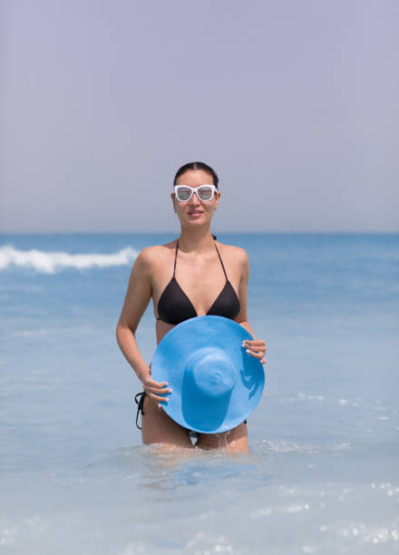 istock brunette in black bikini and hat on the beach 1140832465
