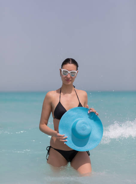 istock sexy brunette model in black bikini and blue hat on the beach 1140833825