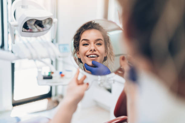 mujer joven mirando en el espejo después de un procedimiento dental - young women smiling women human teeth fotografías e imágenes de stock