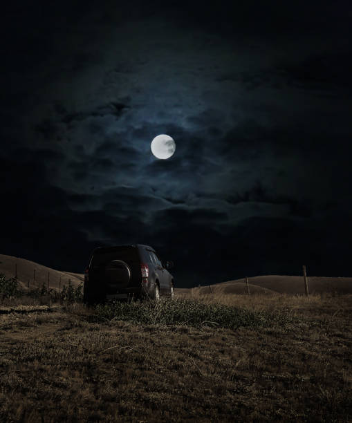SUV is moving on a hilly terrain on a moonlit night