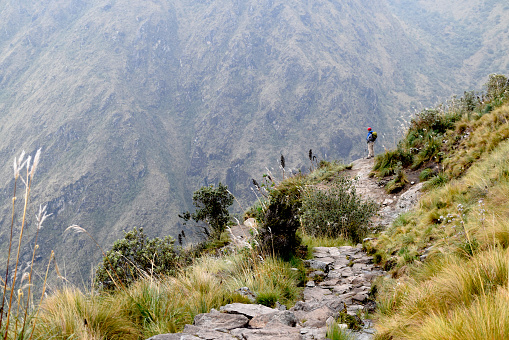 Hispanic man standing on the historical Inca trail, which goes through the mountains to Machu Picchu. Man unplugged from the busy city life, enjoying the view and peacefulness. Photo taken on the Inca trail, Peru on November 3, 2018