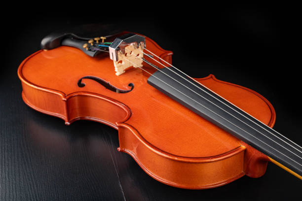 istock Beautiful new shiny violin on a dark table. Musical string instrument prepared for work. Dark background. 1140845220