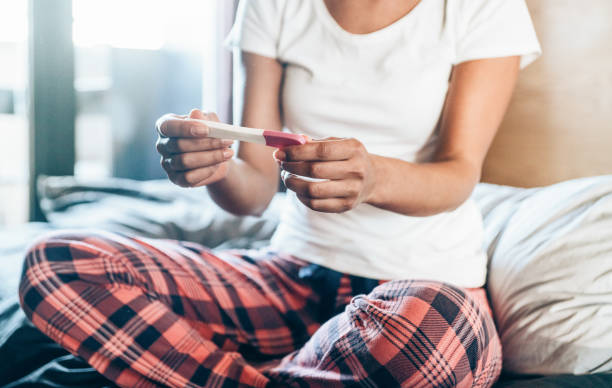 sad young woman with pregnancy test at home - ovulação imagens e fotografias de stock