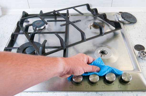 człowiek czyszczenia kuchenka gazowa. - cleaning stainless steel steel domestic kitchen zdjęcia i obrazy z banku zdjęć