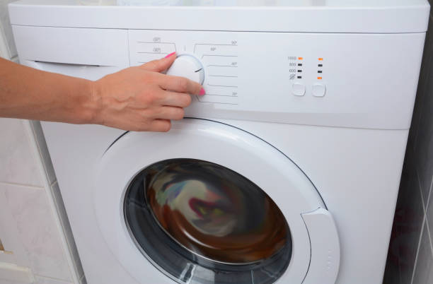 istock View on how a woman is choosing a washing mode on the washing machine. 1140851734