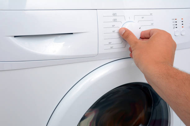 istock View on how a man is turning on of the washing machine. 1140851755