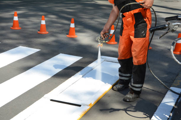 istock Technical road man worker painting and remarking pedestrian crossing lines on asphalt surface using paint sprayer gun. 1140852611