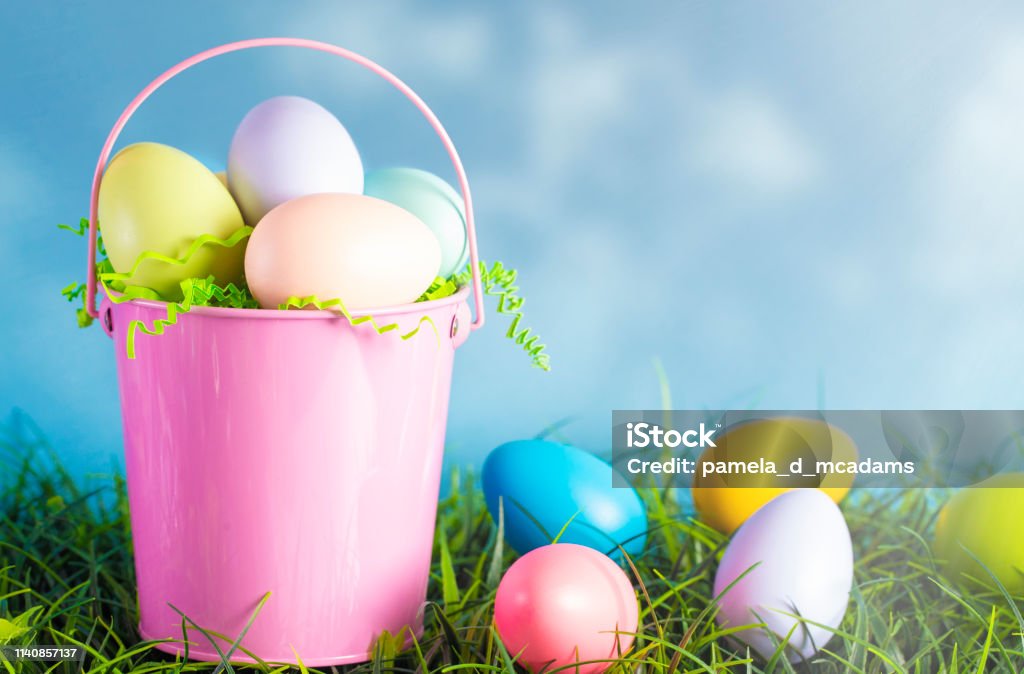 A Pink Easter Basket Filled with Diecorated Eggs on a Clear Blue Sky Spring Day Artificial Stock Photo