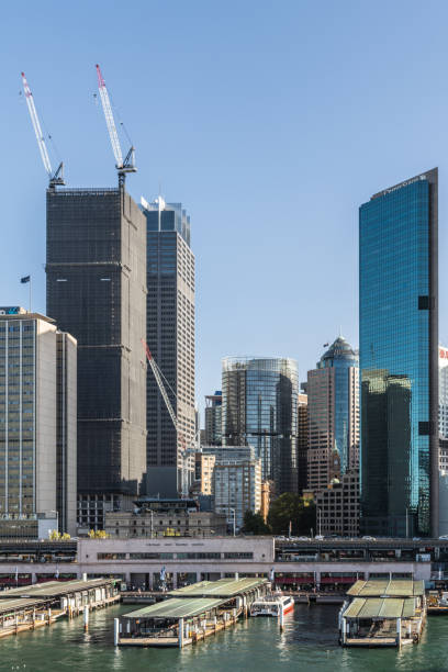 Part of Ferry terminal and Circular Quay Railway station, Sydney Australia. Sydney, Australia - Sydney, Australia - February 12, 2019: Part of ferry terminal and Circular Quay Railway Station plus skyline in back. Highrises under construction with cranes. Evening shot with light blue sky. ferry terminal audio stock pictures, royalty-free photos & images