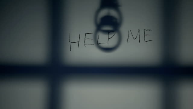 Help me phrase written on prison wall, handcuffs and bars shadow, despair