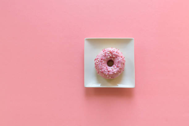 Overhead view of pink donut on white plate
