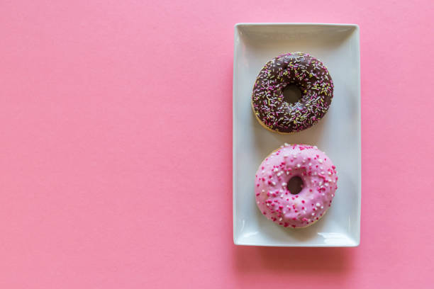 istock Overhead view of two fancy donuts on pink background 1140880795