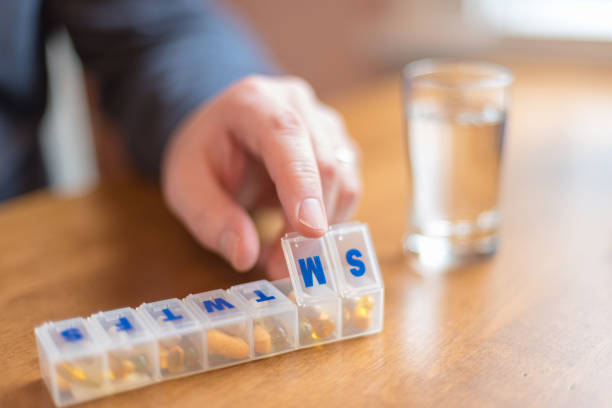 Man using a pill holder to organize daily vitamins and supplements stock photo