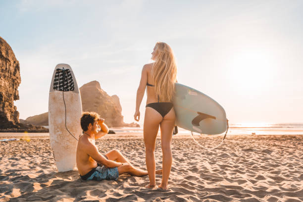 coppia in spiaggia per il surf con tavole da surf. - surfing the net foto e immagini stock