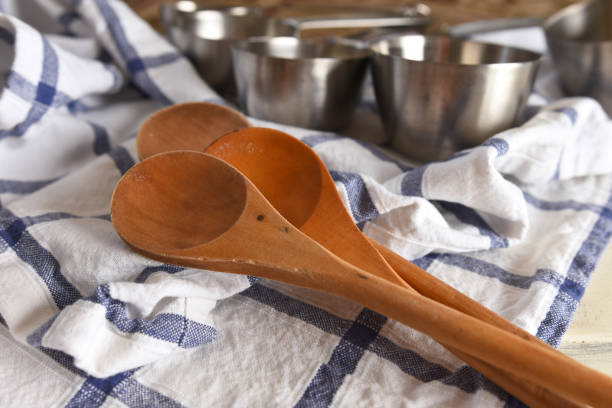 A close up image of several wooden mixing spoons and tin measuring cups.