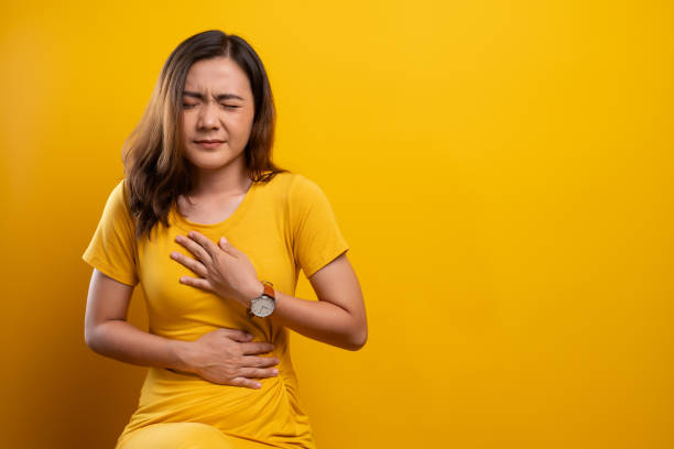 Woman has stomachache isolated over yellow background Woman has stomachache isolated over yellow background gastroesophageal reflux disease photos stock pictures, royalty-free photos & images