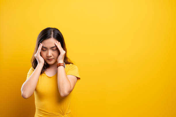 istock Woman has headache isolated over yellow background 1140891135