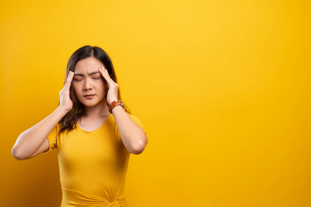 istock Woman has headache isolated over yellow background 1140891161