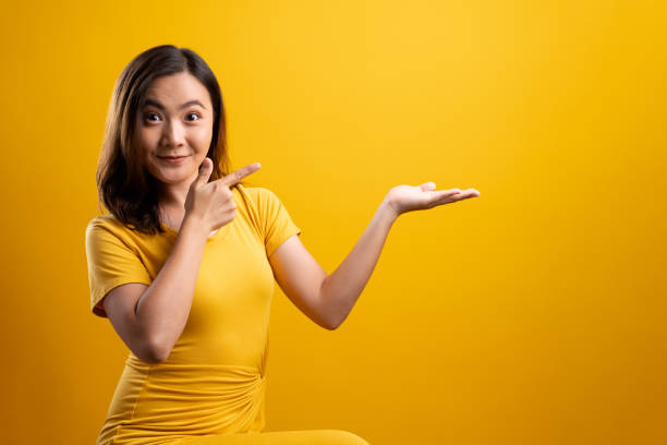 istock Woman pointing to copy space isolated over yellow background 1140892020