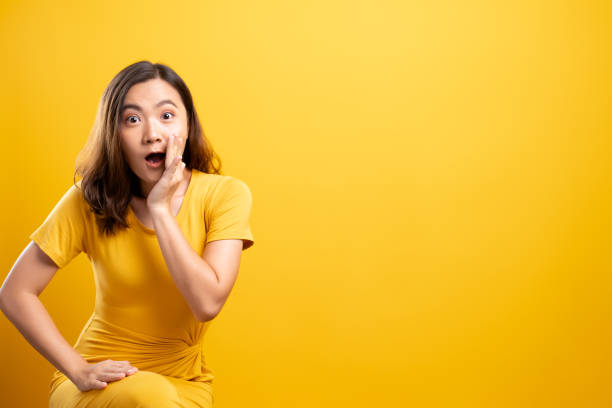 istock Woman make gossip gesture isolated over yellow background 1140893096