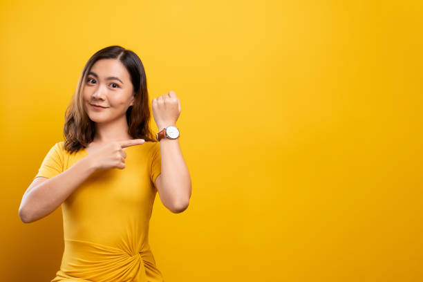 szczęśliwa kobieta trzymająca rękę z zegarkiem na rękę odizolowanym na żółtym tle - happy ending zdjęcia i obrazy z banku zdjęć