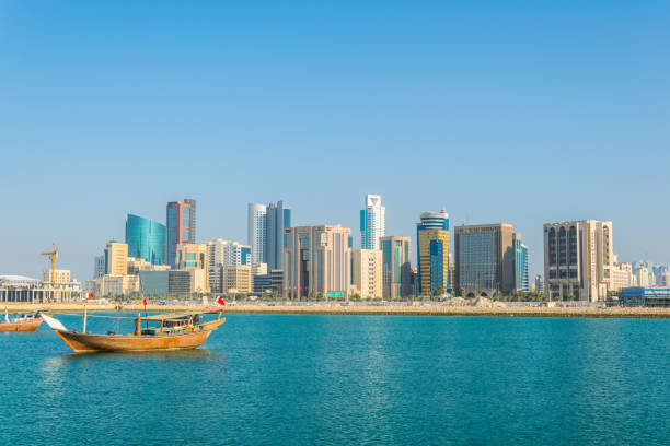 skyline von manama mit einem dhow boot, bahrain. - bahrain stock-fotos und bilder