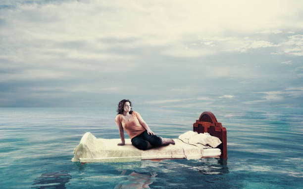 istock Woman sitting on a bed floating in the ocean. 1140907281