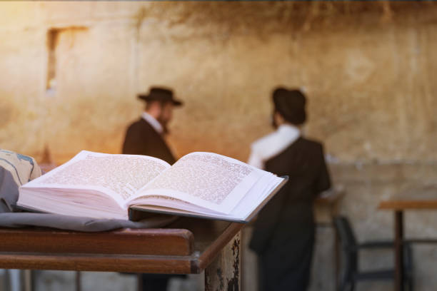 jewish bible on table, wailing western wall, jerusalem, israel. book of the torah-the pentateuch of moses is open on the prayer table on the background of praying orthodox jews. - yiddish imagens e fotografias de stock