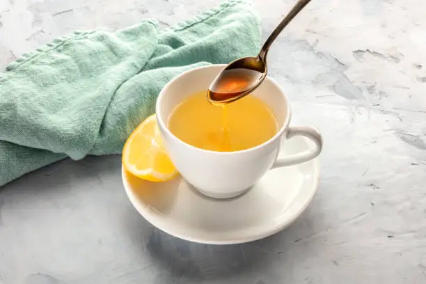 A photo of a cup of green tea with lemon and honey with a place for text