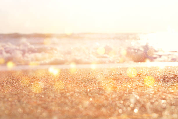 background image of sandy beach and ocean waves with bright bokeh lights