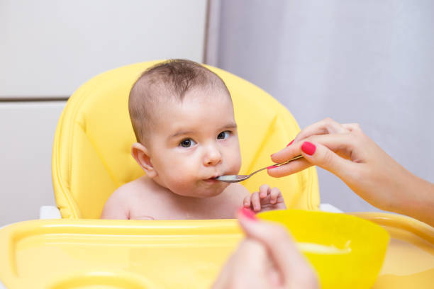 istock mother feeding her baby son with fruit puree 1140918166