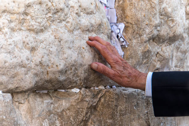 main de l’homme priant sur le mur occidental à jérusalem. un vieux juif âgé touche une pierre sacrée dans la prière. rite traditionnel pour les touristes et les juifs à jérusalem israël. - middle the western wall jerusalem israel photos et images de collection