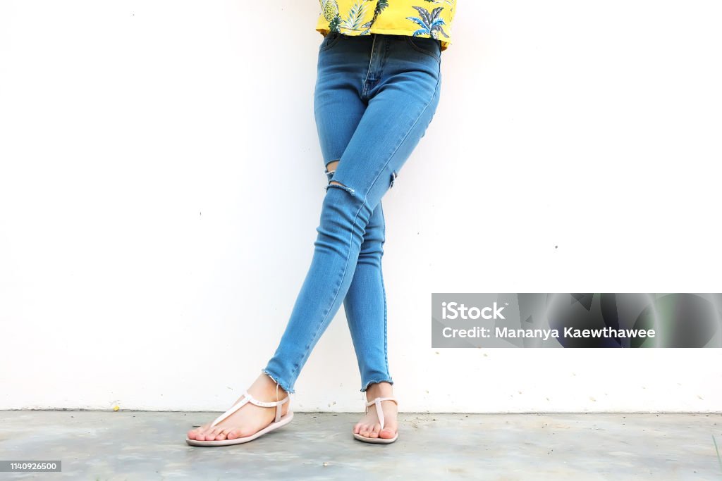 Summer Fashion Nude Sandal (Footwear) and Slim Legs in The City,Street Style. Beautiful Slim Woman Legs with Nude Sandals and Lack Blue Jean on Concrete Floor Background Adult Stock Photo