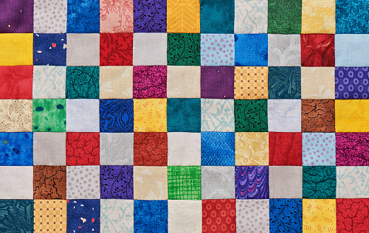 Colorful detail of quilt sewn from square pieces