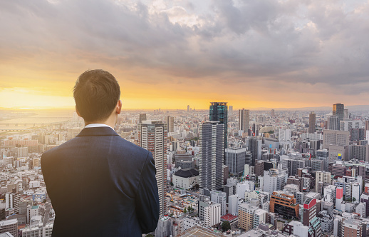 Businessman in blue suit and Osaka city in Japan at sunset. Business concept