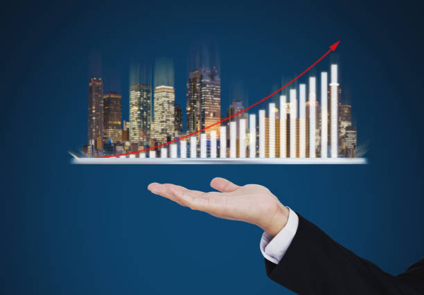 real estate business investment concept. businessman hand holding digital tablet with buildings hologram and increasing bar chart and graph - financial occupation graph chart blue imagens e fotografias de stock