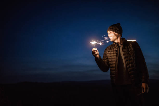 Young happy man with a sparklers by night.