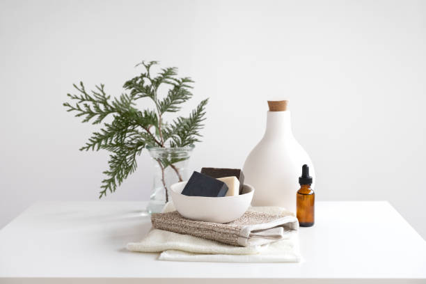 Natural Soaps Stacked on Bamboo Bath Scrubbing Mitt and Towels Vegan, natural soaps in handmade ceramic bowl stacked on washi and bamboo fibre cleansing mitt and cloths, aromatherapy oil. Cedar branches in reusable mason jar. body care and beauty photos stock pictures, royalty-free photos & images